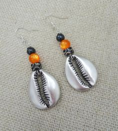 The silver plated cowrie is beaded with carved and glass beads. The earrings will come with back stoppers. If you have any questions please feel free to contact us at anytime. All shipping options are available. All items will be shipped out Monday through Friday. Receipts will be emailed out for immediate access. All items will be shipped out carefully and every shipment can be made with extra insurance upon request. All other concerns and details can be found in our policy section. Our goal is for your 100% satisfaction. If you would like to make a large order please contact us for a coupon code. Our products are not intended for babies or children as we use small pieces, wires and beads. These can be dangerous to them when unsupervised. Gift boxes and gift messages are available for you Beach Beaded Metal Earrings, Metal Beaded Earrings For Beach, Beach Jewelry With Polished Oval Beads, Traditional Metal Jewelry For Beach, Beaded Metal Drop Earrings For Beach, Metal Beaded Drop Earrings For Beach, Beach Jewelry With Teardrop Dangling Beads, Teardrop Dangling Beads Jewelry For Beach, Beach Teardrop Jewelry With Dangling Beads