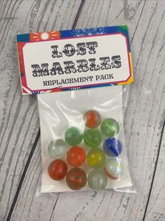 a bag of gummy bears sitting on top of a wooden floor next to a sign that says lost marbles