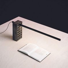 an open book sitting on top of a table next to a lamp and a phone