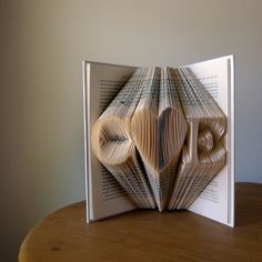 an open book with folded pages sitting on top of a table