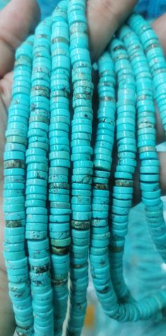 a person holding several turquoise beads in their hands