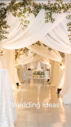 an aisle with white draping and greenery on the ceiling is decorated for a wedding