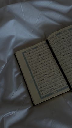 an open book sitting on top of a white sheet