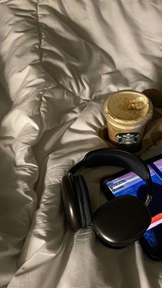 a cup of coffee and headphones on a bed