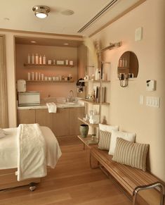 a room with a bed, couch and shelves on the wall above it that are filled with personal care items