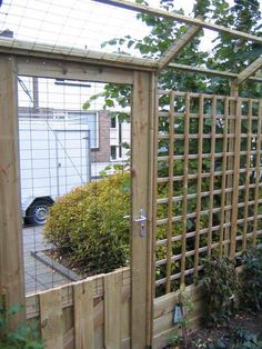 a wooden trellis next to a garden with plants in the foreground and a car parked on the other side