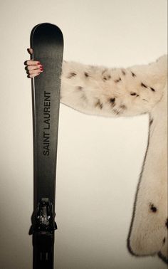 a woman holding a snowboard in her right hand and wearing a white fur coat