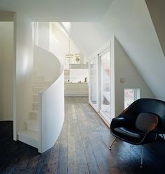 a chair sitting in the middle of a room next to a spiral staircase