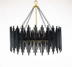 a chandelier made out of black and gold sticks hanging from a metal chain