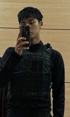 a young man taking a selfie in front of a mirror with his cell phone