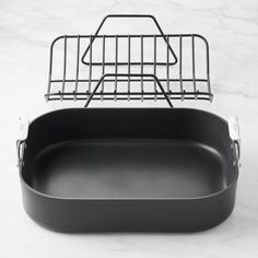 an empty roasting pan with a wire basket on the top, sitting on a marble countertop