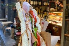 a large sandwich with meat and vegetables on it sitting in front of a store window