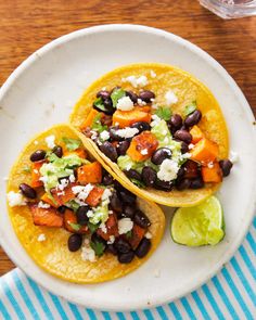 two tacos with black beans, avocado and feta cheese on top