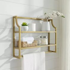 a bathroom shelf with towels, vases and other items on it in front of a white wall