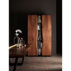 a wooden cabinet sitting next to a table filled with vases and bottles on top of it