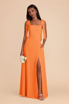 a woman wearing an orange bridesmaid dress with one shoulder and slit down the side