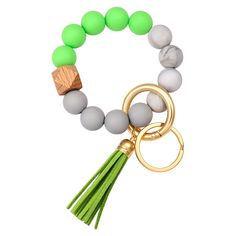 a green and white beaded bracelet with a wooden charm on the front, two tassels hanging from it