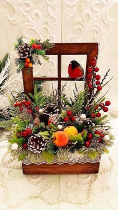 a bird sitting on top of a wooden box filled with fruit and greenery next to pine cones