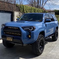 a blue toyota truck parked in front of a garage with its lights on and the door open