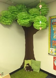 an office cubicle with a tree and stuffed animal on the floor in front of it