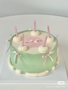 a green cake with white icing and pink candles