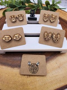 four pairs of dog head studs are on top of a piece of wood,