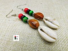 These are handmade African cowrie dangle earring. These are made and beaded with wood earrings which are Pan African colored beads. The earrings are 27.5 inches long. The earrings are a shell dangle earrings. The earrings will come with back stoppers. The earrings can also come in clip on and wire please scroll down for the option.  If you have any questions please feel free to contact us at anytime.  Tips and Suggestions for Clip On (Non Pierced) Earrings to fit your ears comfortably: Clip on feels loose: Go slow and adjust carefully 1.Use your fingers or a small pair of pliers to gently open the fold, bringing the pad closer to the back of the earring.   2.Use pliers and slowly, gently tighten up the U shape at bottom 3.Try clip on pads Clip on feels tight:  Test frequently as your adjus Traditional Adjustable Earrings With Wooden Beads, Traditional Wooden Beads Dangle Jewelry, Traditional Adjustable Wooden Bead Earrings, Traditional Dangle Jewelry With Wooden Beads, Cowrie Shell Earrings, Non Pierced Earrings, Pan African, Red Black Green, Loc Jewelry