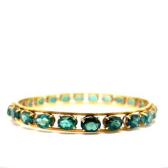 This statement bangle bracelet features a a collection of green tourmalines in 18 karat yellow gold. One of a kind and stylish. Twenty-four (24) 1.35 carat oval cut tourmalines decorate the 8.5 inch bangle. Radiant & timeless in design. A structured style of modern bangle to add a pop of color to your wardrobe. A great gift for jewelry lovers. Tourmaline gemstones symbolize active compassion, vitality, and abundance. A chic gift for any special occasion! Pink Tourmaline Jewelry, Rose Gold Bangle Bracelet, Modern Bangle, 18k Gold Bangle, Flush Set Diamond, Rose Gold Bangle, Sterling Silver Bangle Bracelets, Tourmaline Jewelry, Gold Bracelet For Women