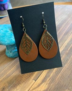 a pair of brown leather earrings with leaves on them