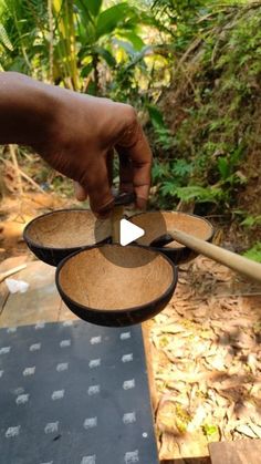 a person is holding two wooden bowls in their hands