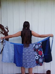 a woman holding several pieces of cloth in front of a white wall with shoes hanging on it