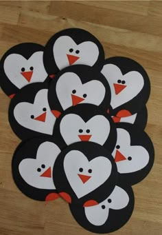 a bunch of penguins that are sitting on top of a wooden table with hearts painted on them