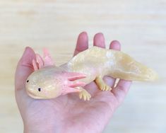 a hand holding a toy gecko in it's palm