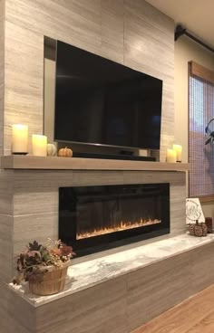 a living room with a fireplace and television mounted on the wall next to a potted plant