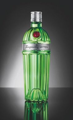 a bottle of green liquid sitting on top of a black table next to a light