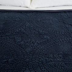 an unmade bed with blue bedspread and white pillows