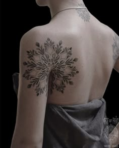 the back of a woman's shoulder with tattoos on her left arm and chest