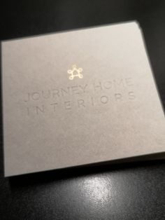 a silver business card with the words journey home interiors written in gold on it's front