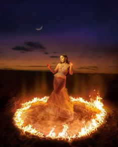 a woman standing in the middle of a circle of fire with her arms spread out