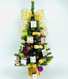 a wine bottle decorated as a christmas tree with tags attached to the top and decorations around it