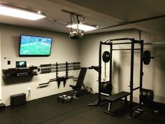 a home gym with equipment and a flat screen tv mounted on the wall above it