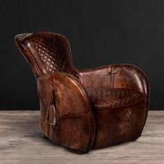 an old leather recliner chair on a wooden floor with dark background and light wood floors