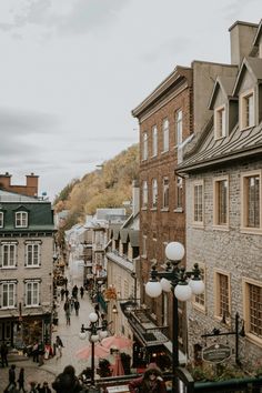 people are walking down the street in an old town with stone buildings and cobblestone streets