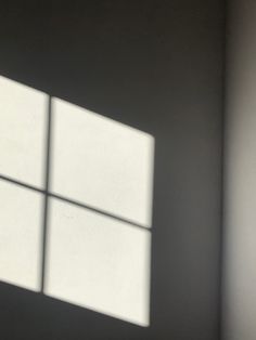 the shadow of a window on a wall in a room with white walls and flooring