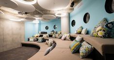 a room filled with lots of pillows on top of couches and round lights above them