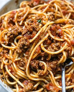 a bowl full of spaghetti with meat and sauce on top, ready to be eaten