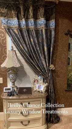 a bedroom with a dresser, lamp and window in the corner that has curtains on it