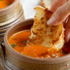 a person dipping some bread into a bowl of soup