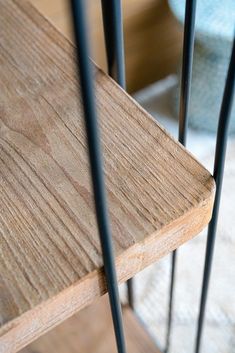 a wooden bench with metal bars on the bottom and sides, in front of a chair