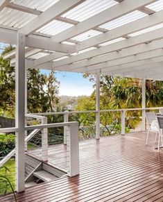 an outdoor dining area with white furniture and wooden flooring on a deck overlooking the trees